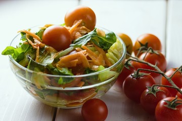 Glass bowl of fresh vegetable salad with little gem, carrot and other veggies