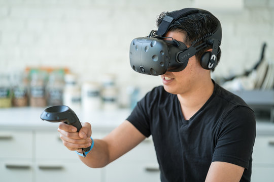 An asian young man uses a virtual reality headset.
