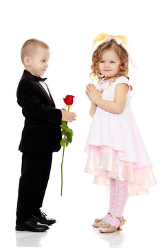 The boy gives the girl a flower.
