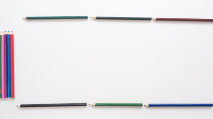 Many different colored pencils on a white background. Place for your text