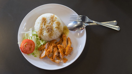Fried chicken with steamed rice with dressing sauce and slice tomato and cabbage