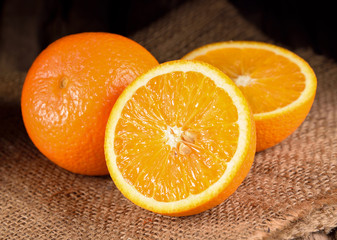 Fresh oranges with slices on wooden background.