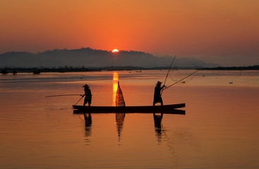 Silhouette fisherman trowing the nets on during sunrise,during sunrise,Thailand