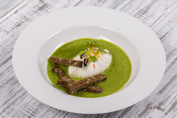 Cooking with local ingredients - poached egg and green healtfy soup, close up