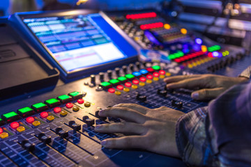 Two hands on audio mix control board console