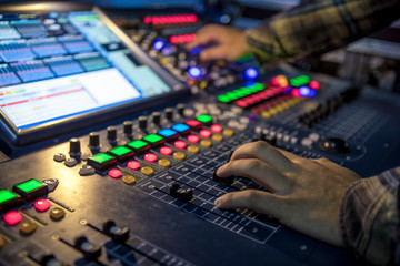 Two hands on a audio mix control board console