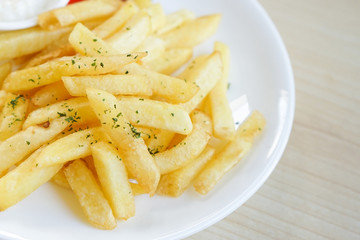 Fresh french fries fried potato sticks parsley topped with ketchup and mayonnaise on white plate	