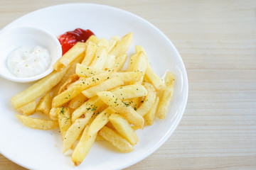 Fresh french fries fried potato sticks parsley topped with ketchup and mayonnaise on white plate	