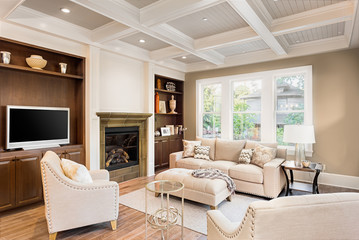 Beautiful living room with fireplace and hardwood floors in new luxury home. Coffered ceiling adds elegant touch. Built-in shelving compliments fireplace and surround. 