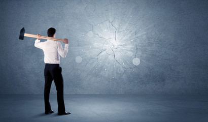 Obraz premium Business man hitting wall with a hammer