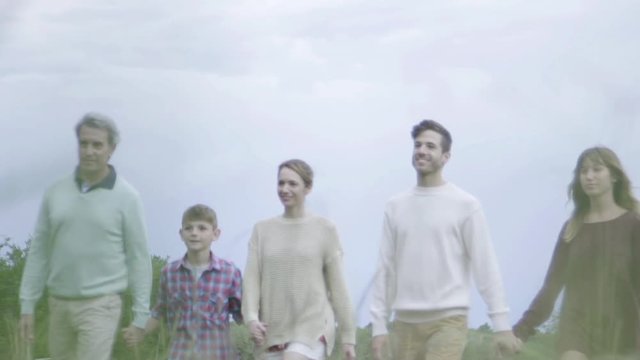 Multi-generation family walking together in field