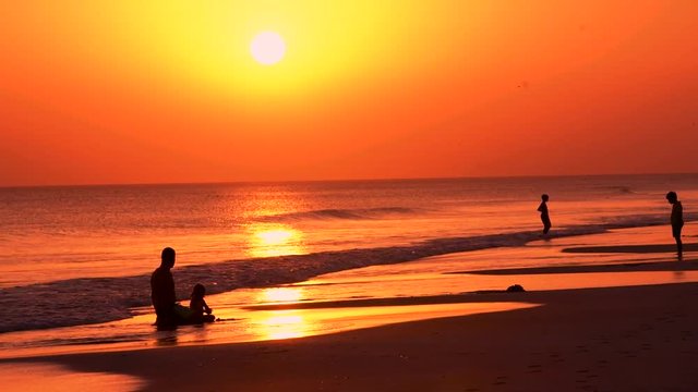 Ojciec z dzieckiem na plaży przy zachodzie słońca