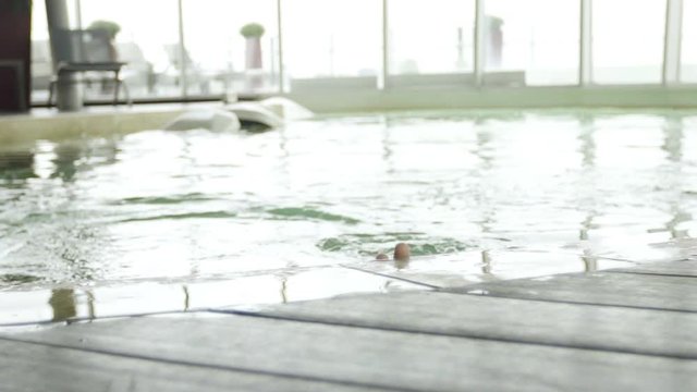 Young woman emerging from water in pool and smiling cheerfully