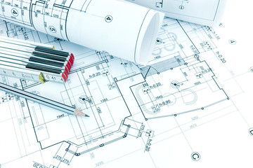 drawing and measurement tools and rolled blueprints on architectural floor plan background