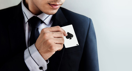 Part of Young Businessman in black suit pulling ace spade card from his pocket