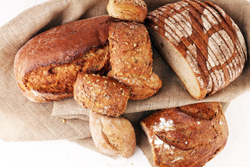 Different kinds of bread and bread rolls on board from above. Kitchen or bakery poster design.