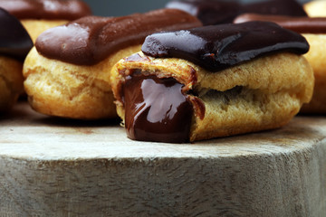 Traditional French dessert. Eclair with chocolate icing. Wooden background