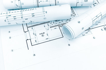 rolled architectural plans and technical drawings on house blueprint background