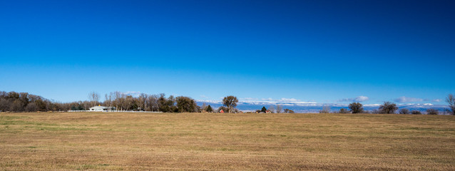 Fototapeta na wymiar Panorama of field in western colorado with farms and snow capped mountains