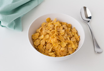 Breakfast cereal of cornflakes in bowl on white table