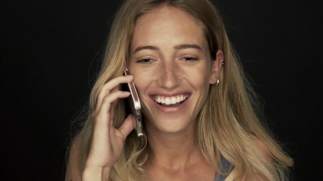 Young woman receiving good news and laughing while talking on cell phone