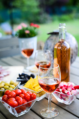 holiday summer brunch party table outdoor in a house backyard with appetizer, glass of rosé wine, fresh drink and organic vegetables