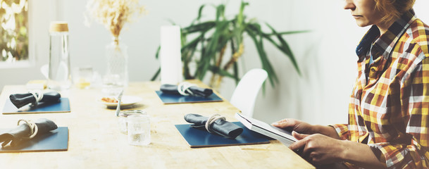 Young girl reads book during breakfast and coffee, female hands close up flipping through magazine pages in home relax atmosphere room on background of natural wooden table, woman is studying, mock