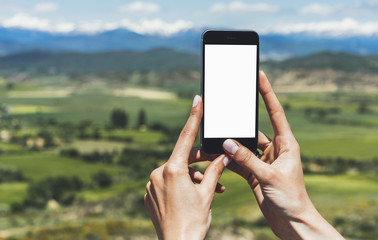 Hipster photograph on smart phone gadget mobile, mock up of blank screen. Traveler hold and using in hand mobile on background mountain landscape horizon. Tourist look map on trip, lifestyle concept