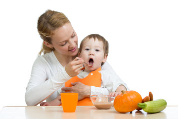 Mom feeding her kid with a spoon. Mother giving food to her little child. Healthy baby food and nutrition.