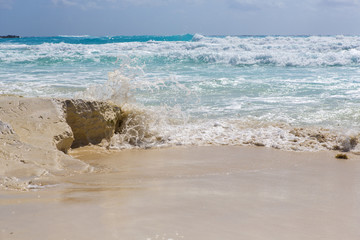 Shore of the Caribbean sea. Water splash and flowing off the cliffs. Sunny summer day.