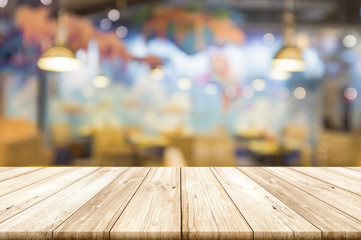 Empty wooden table top with blurred restaurant interior background.
