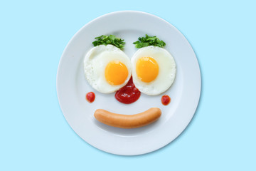 Smiling face frying eggs breakfast on a plate isolated white blue background.
