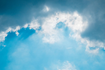 blue sky with dark cloud and tunnel of rays of light shining down with new hope background.