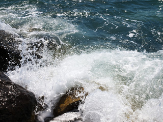 Sea wave crashing rocks on the beach