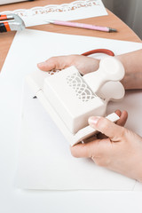 Tools for scrapbooking. A woman uses tools to cut paper.