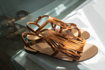 A pair of modern brown leather sandals on white background