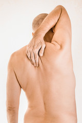 Man massaging his top back, between the shoulders, because of a thoracic vertebrae pain due to a...