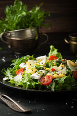 Fresh salad with cherry, arugula, feta, basil and olive oil in a plate