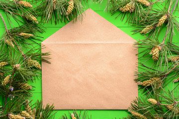 Brown envelope among pine branches on a green wooden background