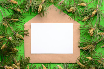 Fototapeta na wymiar A blank piece of paper with an envelope among pine branches on a green wooden background