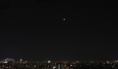夜空に見える月・日本の東京都市景観（左側に新宿の高層ビル群）
