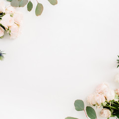 Border frame made of beige rose flowers, eringium flower, eucalyptus branches on white background. Flat lay, top view. Floral background