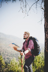 Portrait of adventure young man hiking with map on mountain