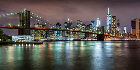Panoramic view of the Brooklyn Bridge with Financial District skyscrapers at twilight and light clouds. Lower Manhattan, New York City