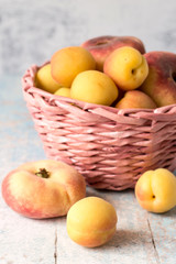 Apricots and peaches.   Ripe juicy apricots and peaches in a pink wicker basket on a wooden background.