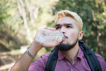 Hiker man drinking water in forest on mountain.