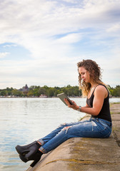 Fototapeta na wymiar young woman use tablet , sitting on lake jetty in summer