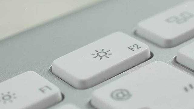 Macro video of keyboard buttons with functions and typing. Man pressing the sun button.
