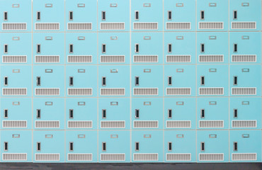 A front on view of a stack of Spring green metal school lockers with combination locks and doors shut as background