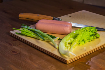 Products on a cutting board salad, onion, and knife